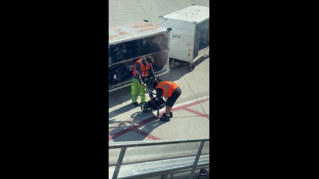 Airport workers struggle to collapse baby stroller for loading