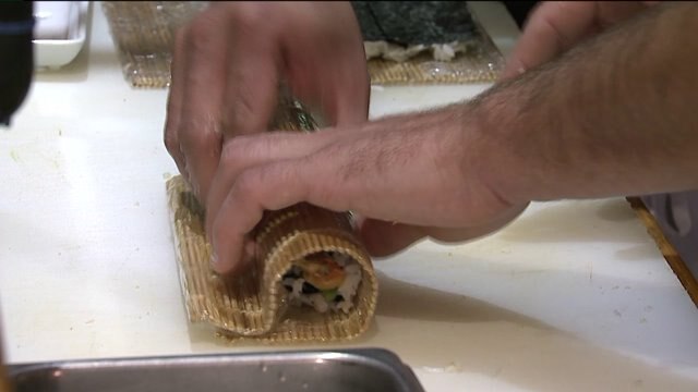 Chip helps prepare a sushi roll