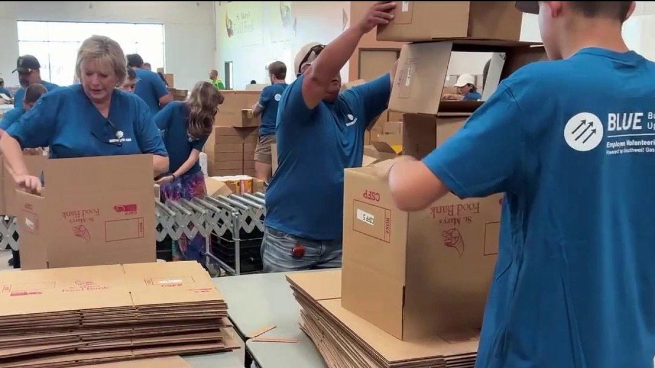 Volunteers help pack boxes for food bank during busy summer season