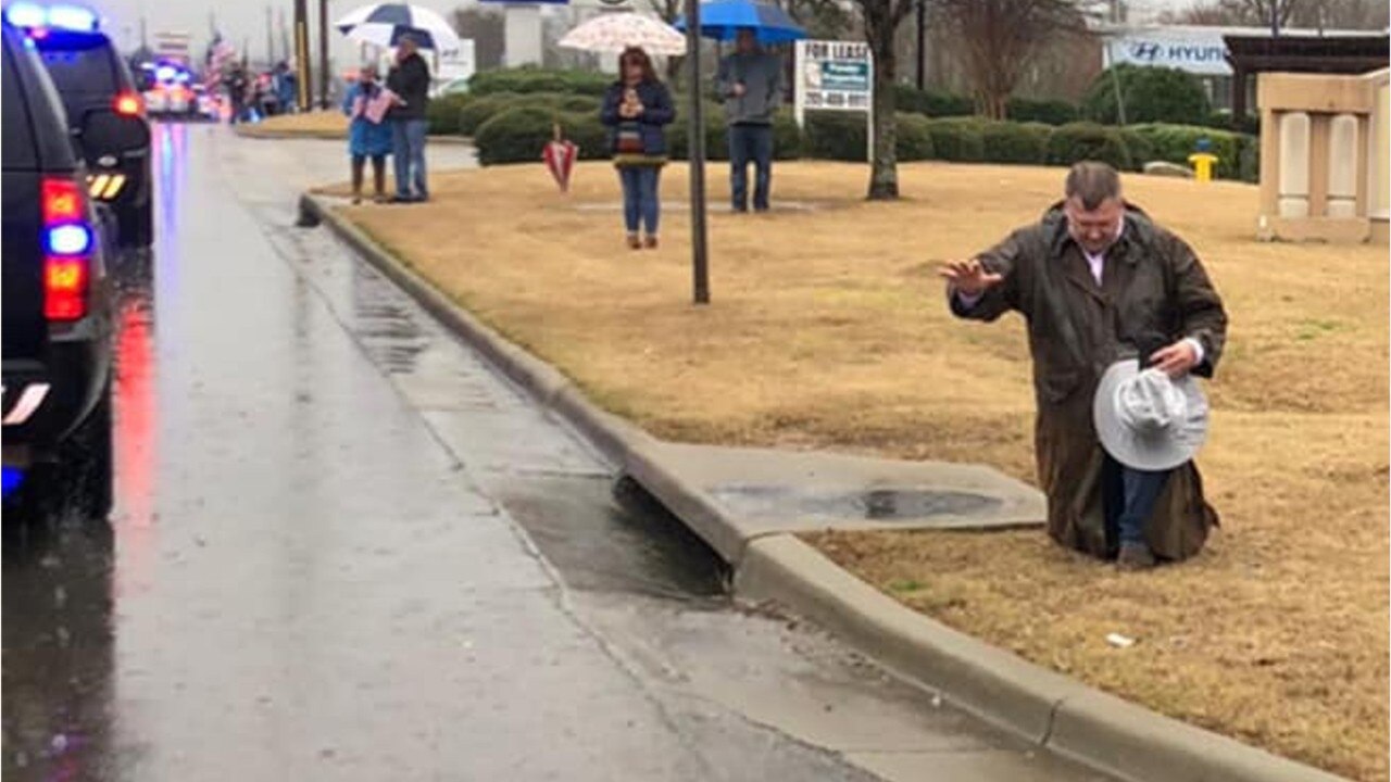 Photo shows a man appearing to pray during a procession for a police officer