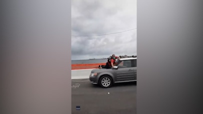 Protester jumps on moving car