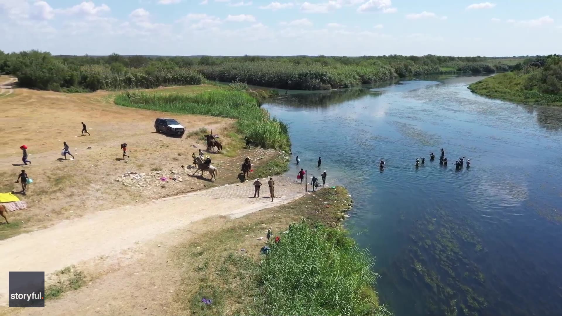 Border patrol agents on horseback attempt to stop migrants crossing the Rio Grande