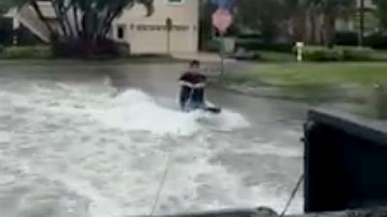 Teens knee board behind pickup truck
