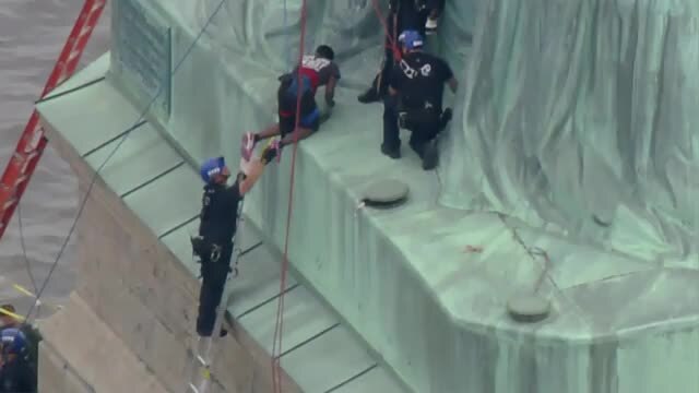 PROTESTER ON STATUE OF LIBERTY (CLIMBING DOWN)