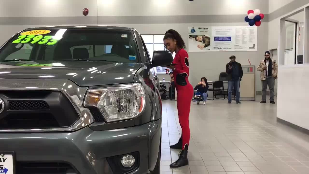 Girl limbos under SUV while carrying trays of drinks