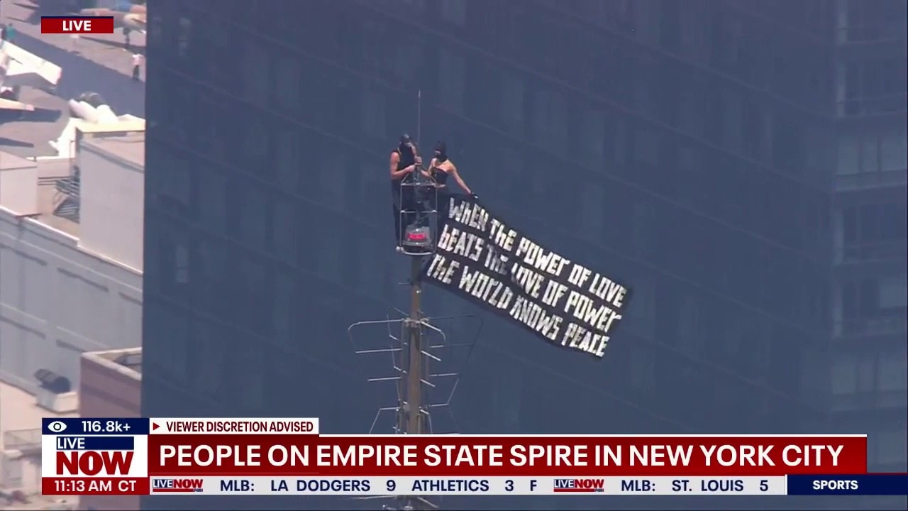 Couple flies banner atop Empire State Building spire