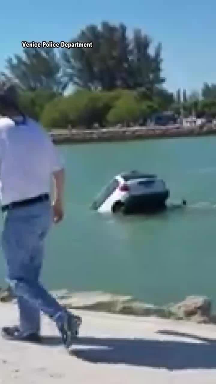 Rescuers try to reach people in submerged car