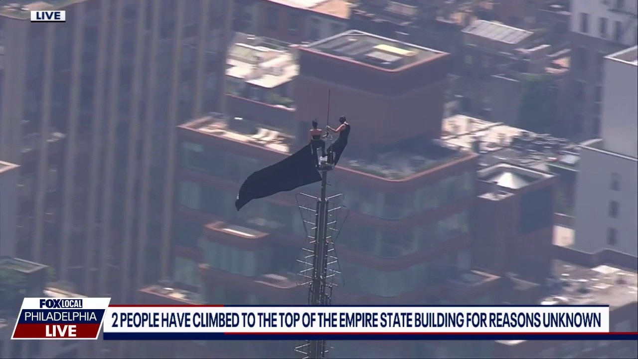 Empire State Building climbers: 2 people scale tower, wave flag