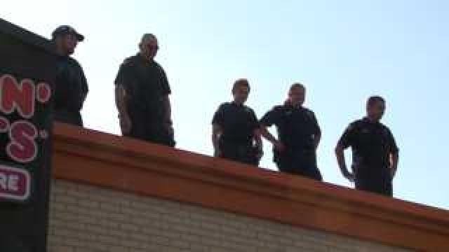 Cops stand atop donut shop roof for charity