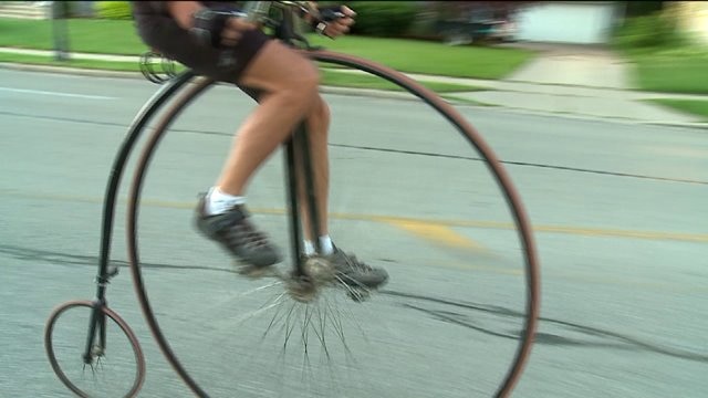 Group of people ride around the world on high-wheel bikes
